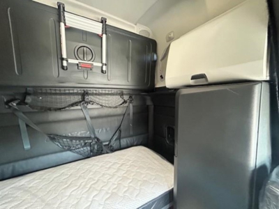 Conventional sleeper cab interior of a 2023 Freightliner Cascadia 126 with bunk area and storage netting.