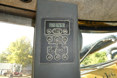 Dashboard display and control panel of a Challenger MT525B with digital readout showing 349 hours and various control icons around. Window and machinery in background.
