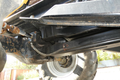 Underbody view of a Challenger MT525B tractor showing hydraulic lines, suspension, and wheel assembly.