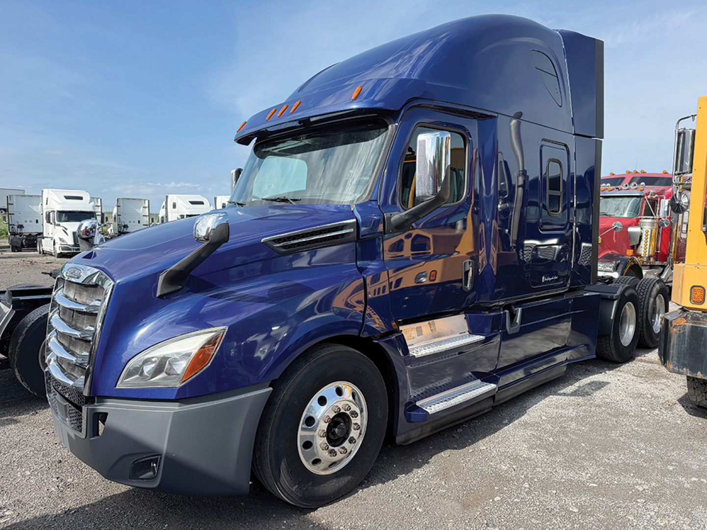 Freightliner Cascadia126 blue semi-truck tractor side view showing aerodynamic mirrors and fuel tanks.