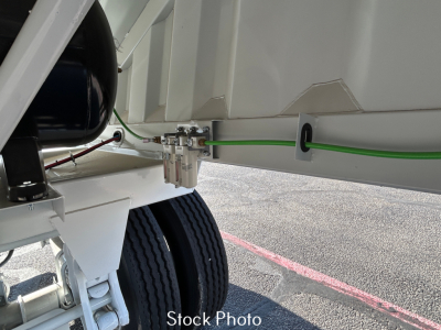 Trailer hydraulic or electrical fitting on a dump trailer with green ground wire and white frame visible, showing side latch and wheel assembly.