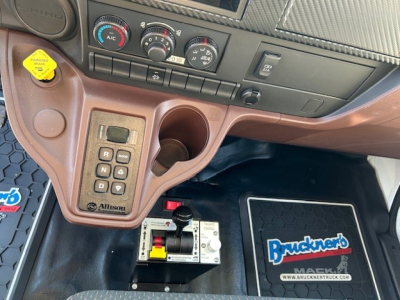 Interior of a 2025 Hino L7 dump truck showing center console with gear controls, cup holder, and Electronic Joystick with Allison badge; floor mat labeled Bruckner's Trucking.