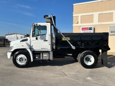 Truck bed in dump configuration with white cab and black dump body, Hino logo on building, VIN 5PVNV7AL0S5T50050 not visible