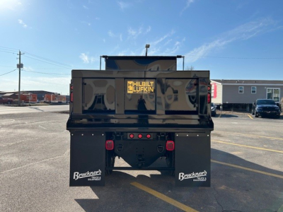 Truck bed rear view of a new 2025 Hino L7 dump truck showing double mud flaps with Bruckner logo and tail lights, stock number 66063, VIN visible.