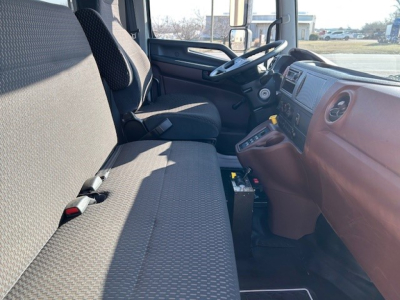 Cab interior of 2025 Hino L7 dump truck showing front bench seat and dashboard with steering wheel, gear shifter, and center console.