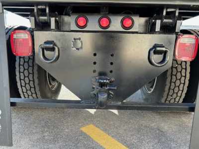 Rear view of a 2025 Hino L7 dump truck showing hitch, bumper, taillights, and rear wheel wells.