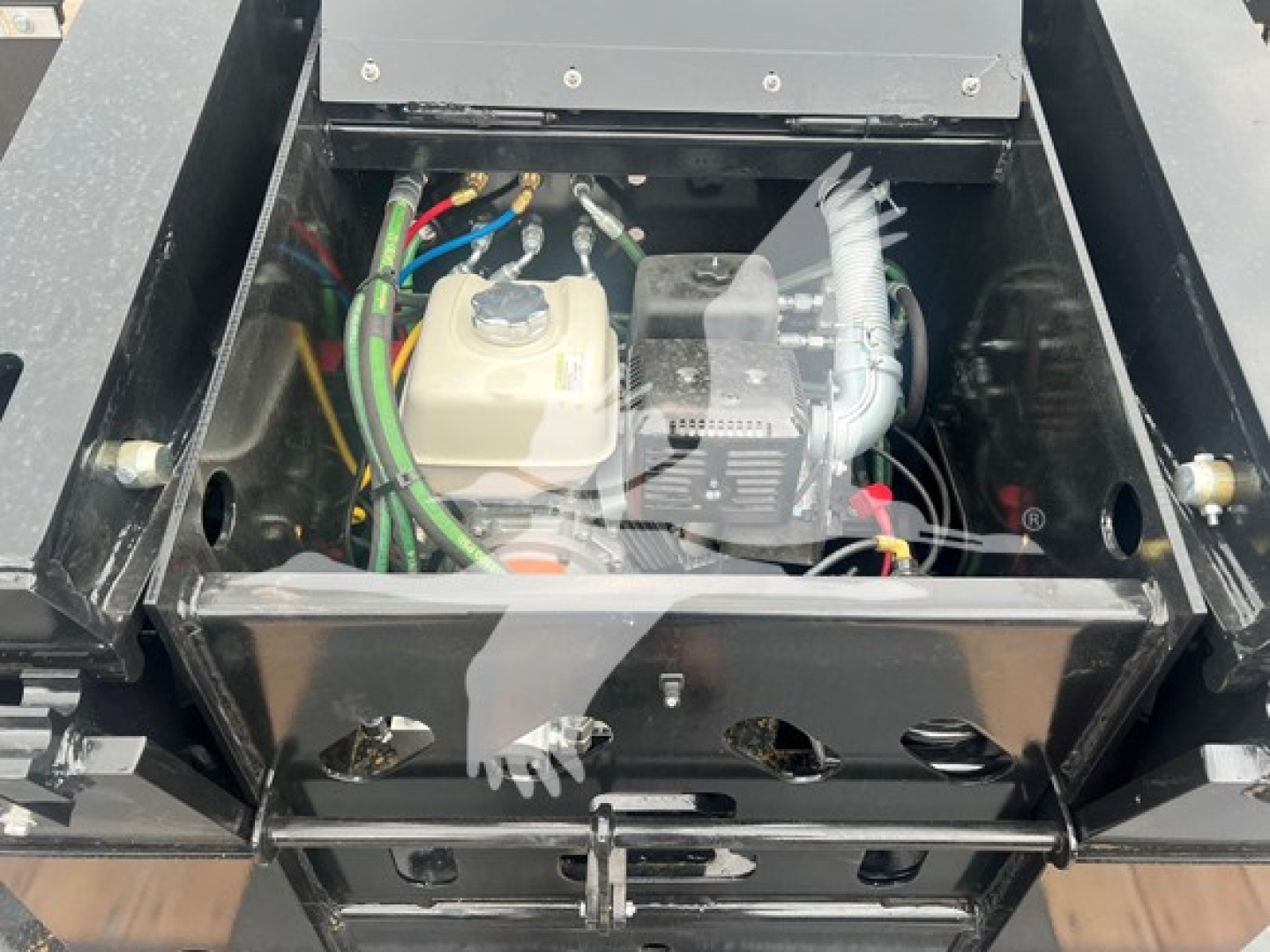 Mini deck trailer engine bay showing electrical wires, coolant reservoir, and compact power unit with hoses and components visible.
