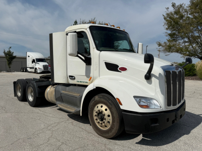 Peterbilt 579 daycab truck front-left view with chrome grille and white cab. Visible text includes Peterbilt badge on grille, fuel tank steps, and side vent. No legible model details or labels clearly readable.