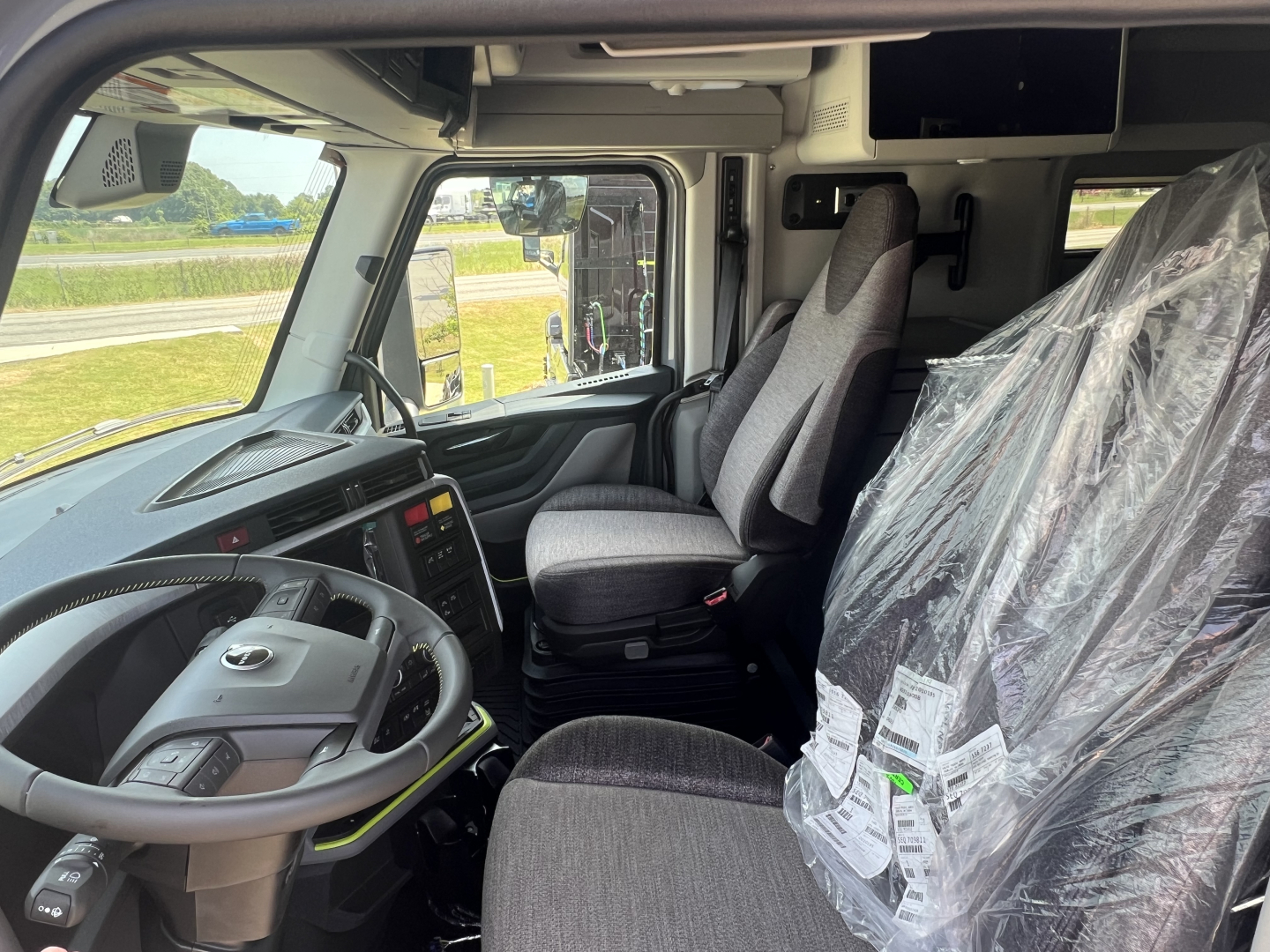 Volvo engine cab interior showing steering wheel, driver seat, and passenger seat in a new Volvo VNL64T860 truck.
