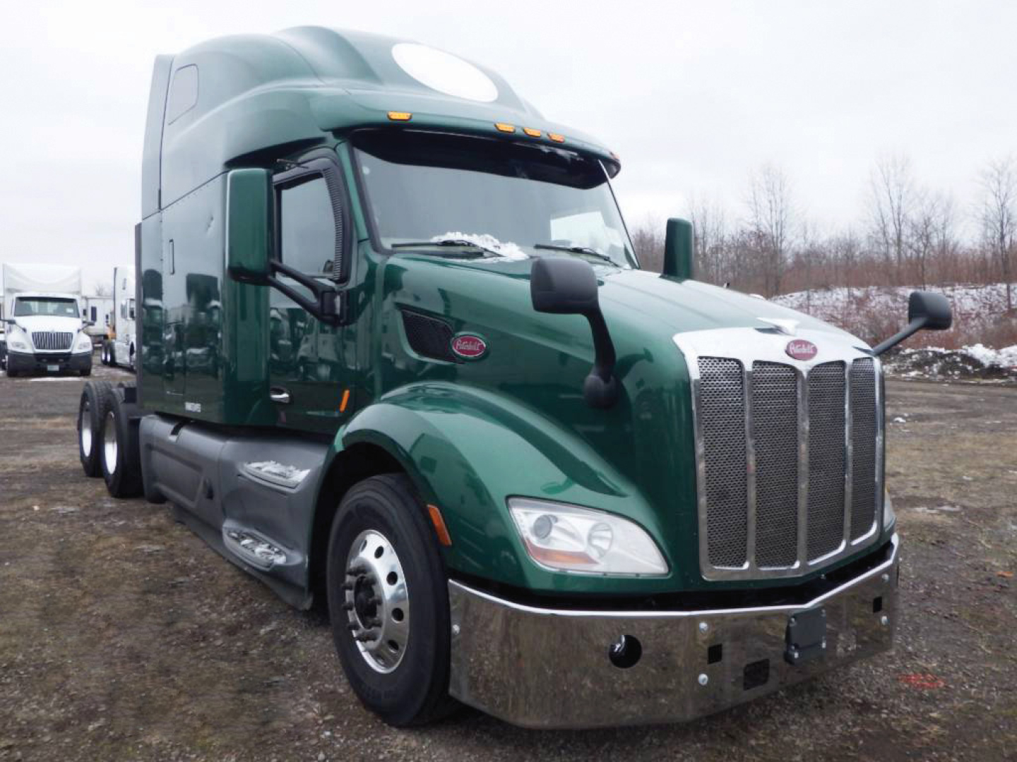 Peterbilt 579 conventional sleeper truck in green, front grille with chrome bumper, dual rear axles, daytime running lights, side mirrors, cab with sleeper section.