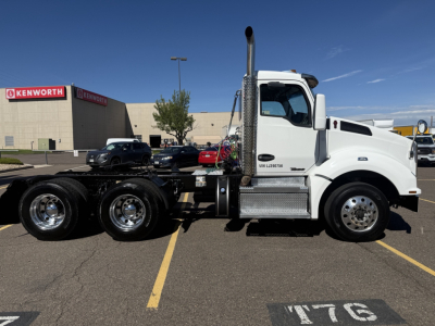 Kenworth T880 tractor side view showing front grille, chrome exhaust stacks, and chassis with dual rear axles in a parking lot.