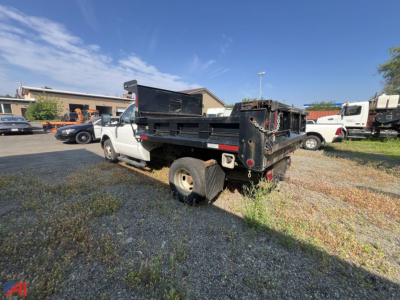 Dump truck bed and rear cab of a white 2015 Ford F-350 Super Duty dumping truck in used condition.