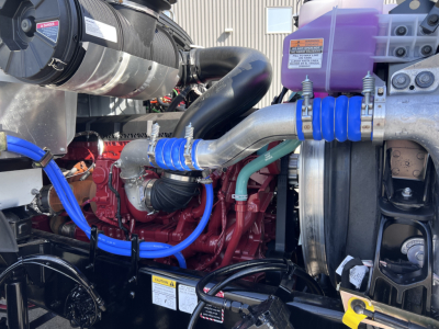 Mack GR64B engine bay showing coolant reservoir and blue silicone hoses with red engine block.