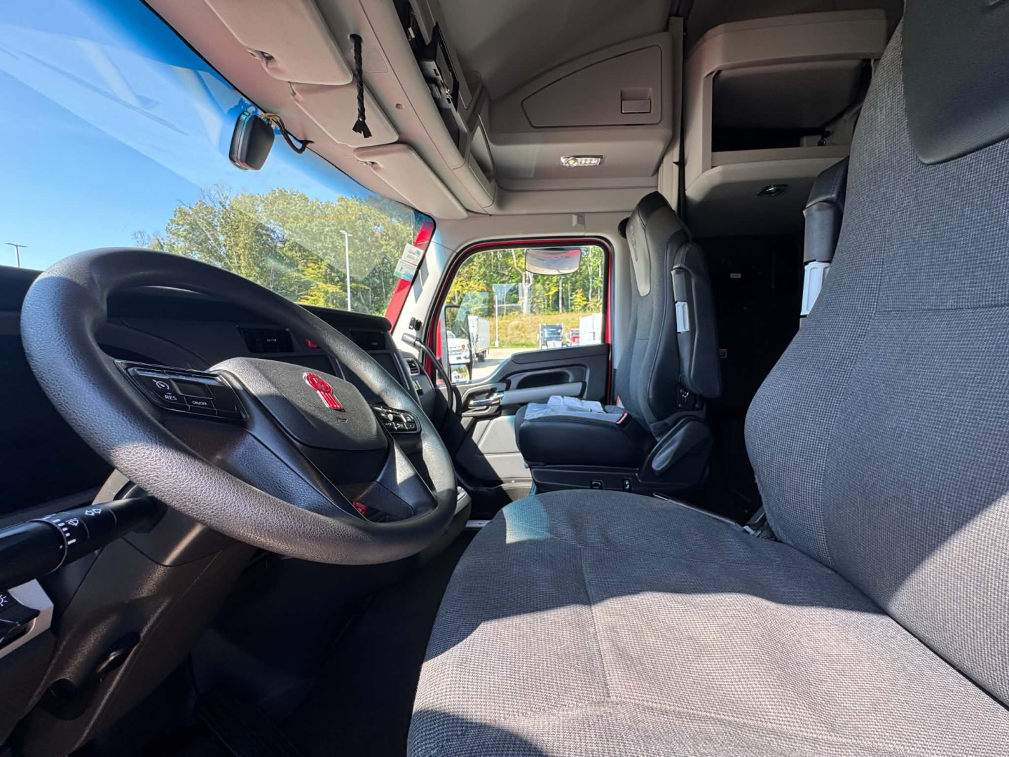 Kenworth T680 truck cab interior with steering wheel, driver seat, and dashboard view.