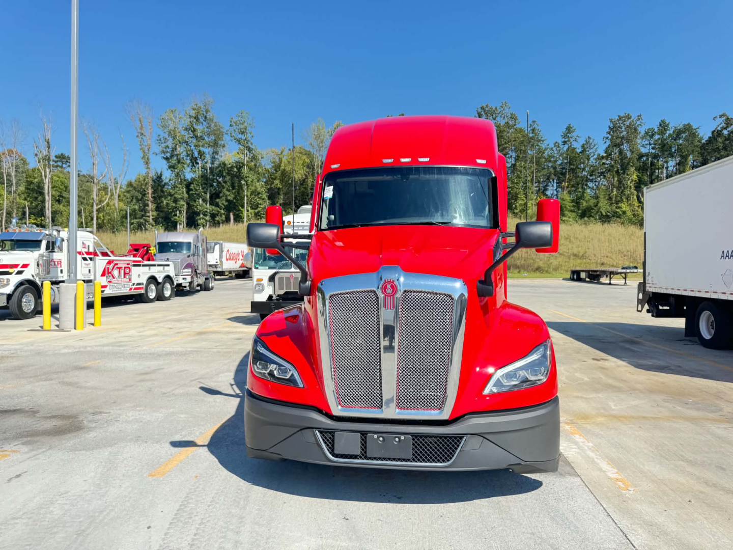Kenworth T680 conventional sleeper truck from front view with red cab.