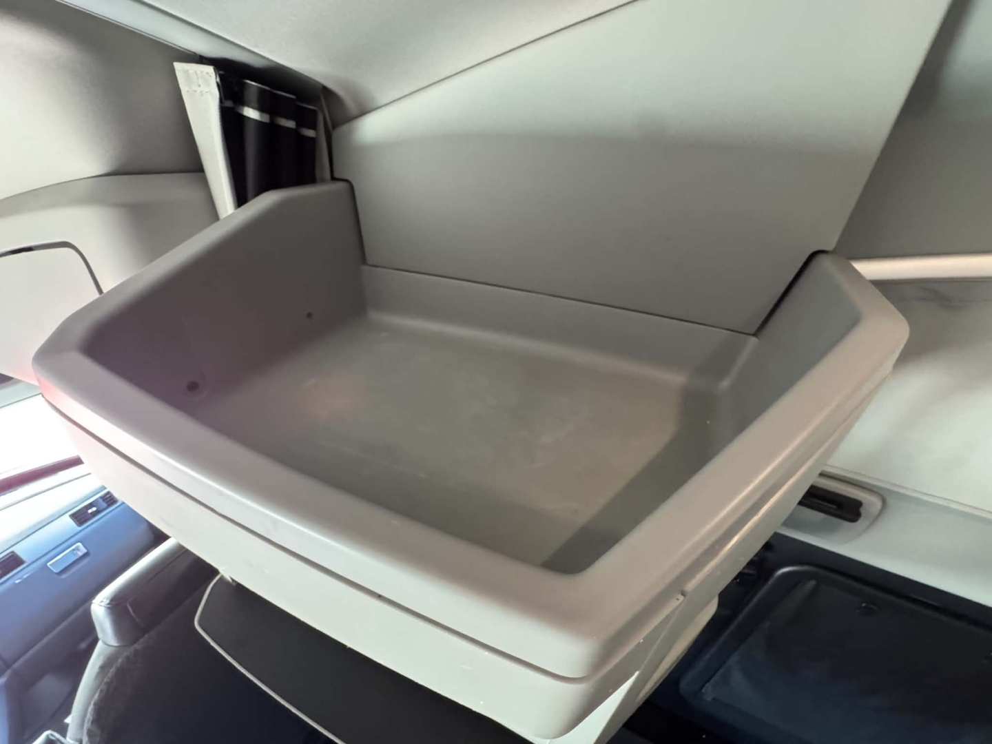 Kenworth T680 cab interior showing open overhead storage bin with molded tray and light-gray plastic dash area.