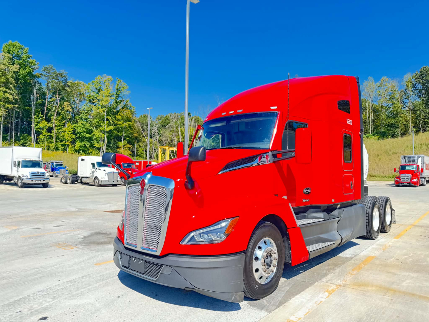 Kenworth T680 tractor in red paint, front three-quarter view, showcasing aerodynamic hood, chrome grille, large headlights, and sleeper cab.