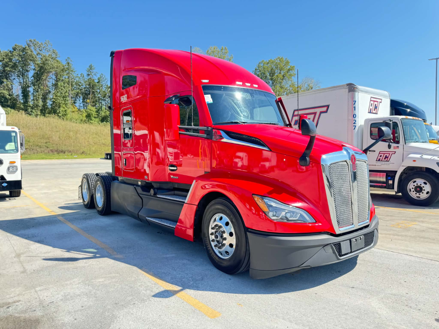 Kenworth T680 sleeper cab tractor in red, front three-quarter view, showing chrome grille, headlights, and aerodynamic body with black lower bumper.