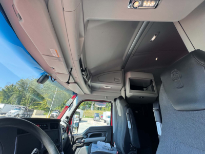 Truck cab interior of a 2024 Kenworth T680 with overhead storage and drivers seat visible.