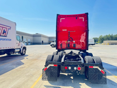 Rear view of a red Kenworth T680 tractor chassis showing fifth wheel, dual rear axles, mudflaps, and connectors. Stock number 56302 and utility area visible.