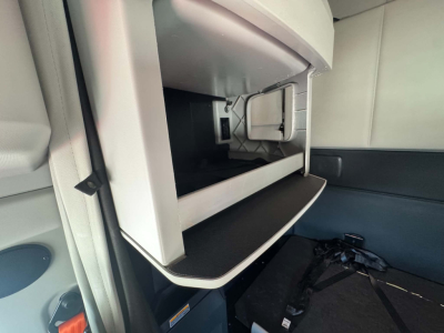 Kenworth T680 sleeper cab interior showing open overhead storage compartment and dashboard area.