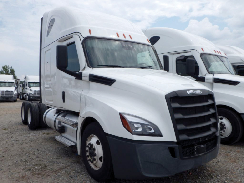 Freightliner Cascadia126 sleeper truck in a lot showing front grille and headlights.