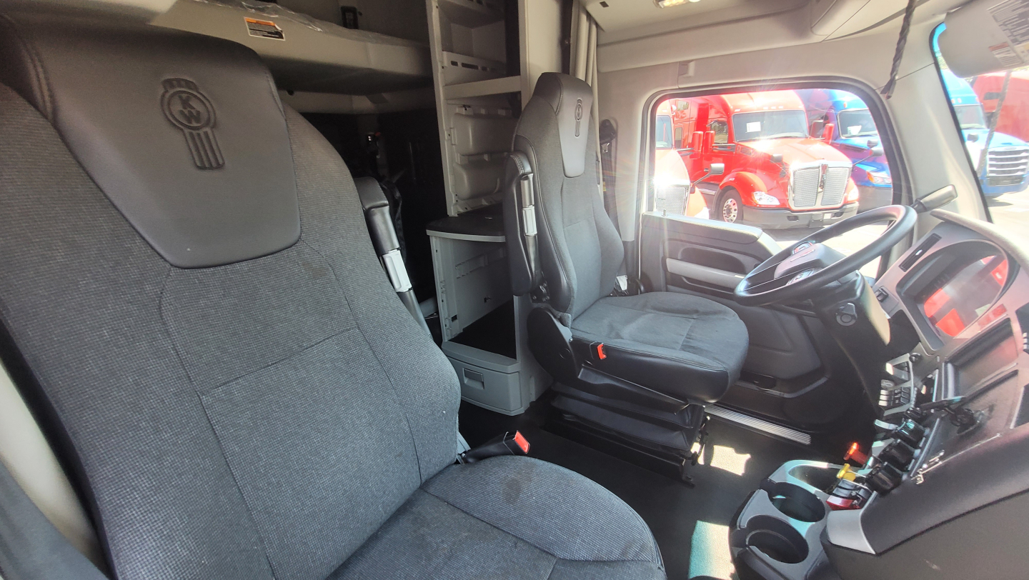 Kenworth T680 cab interior view showing driver seat and front passenger seat with dashboard and steering wheel.