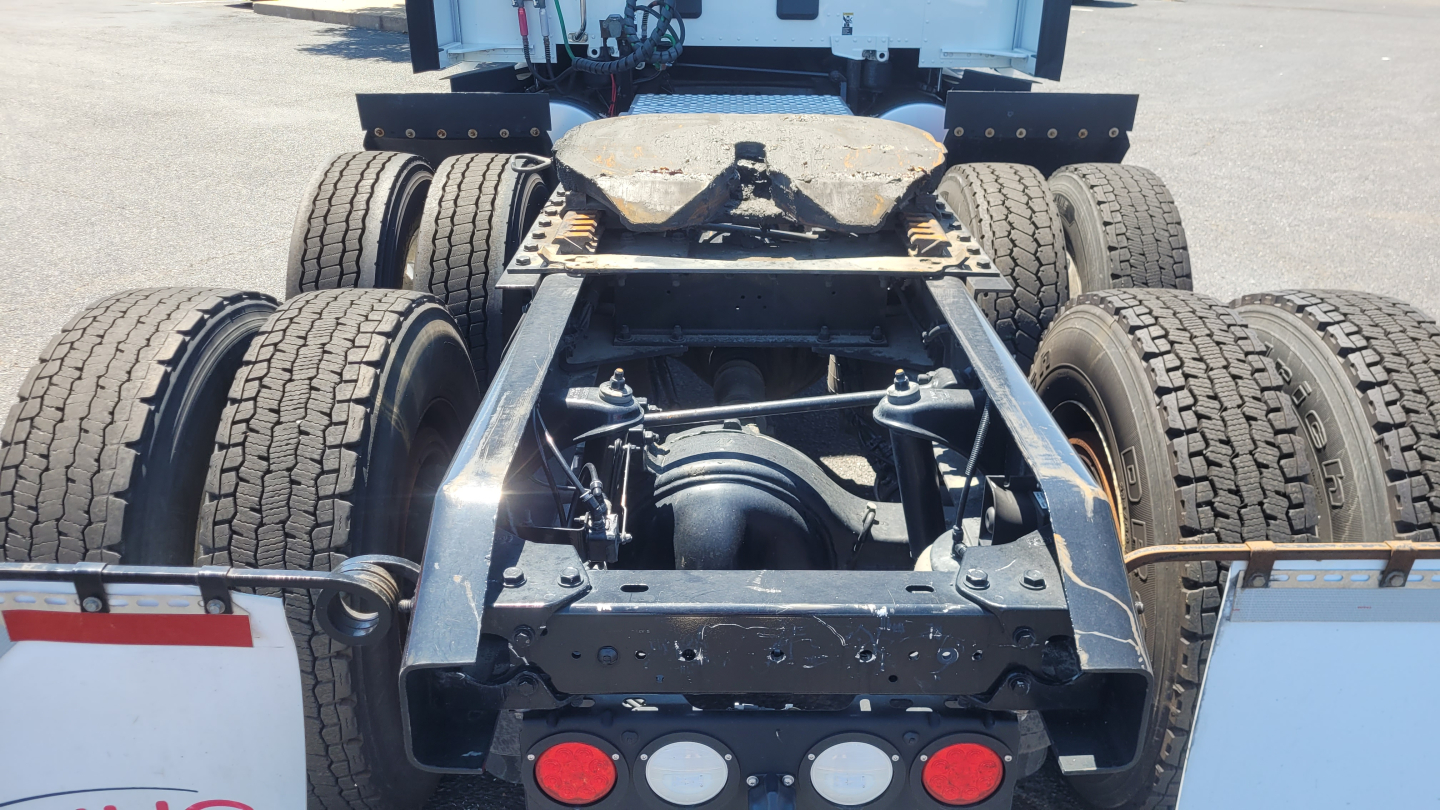 Truck chassis rear view showing fifth wheel, dual rear axles, and tires; no cab visible