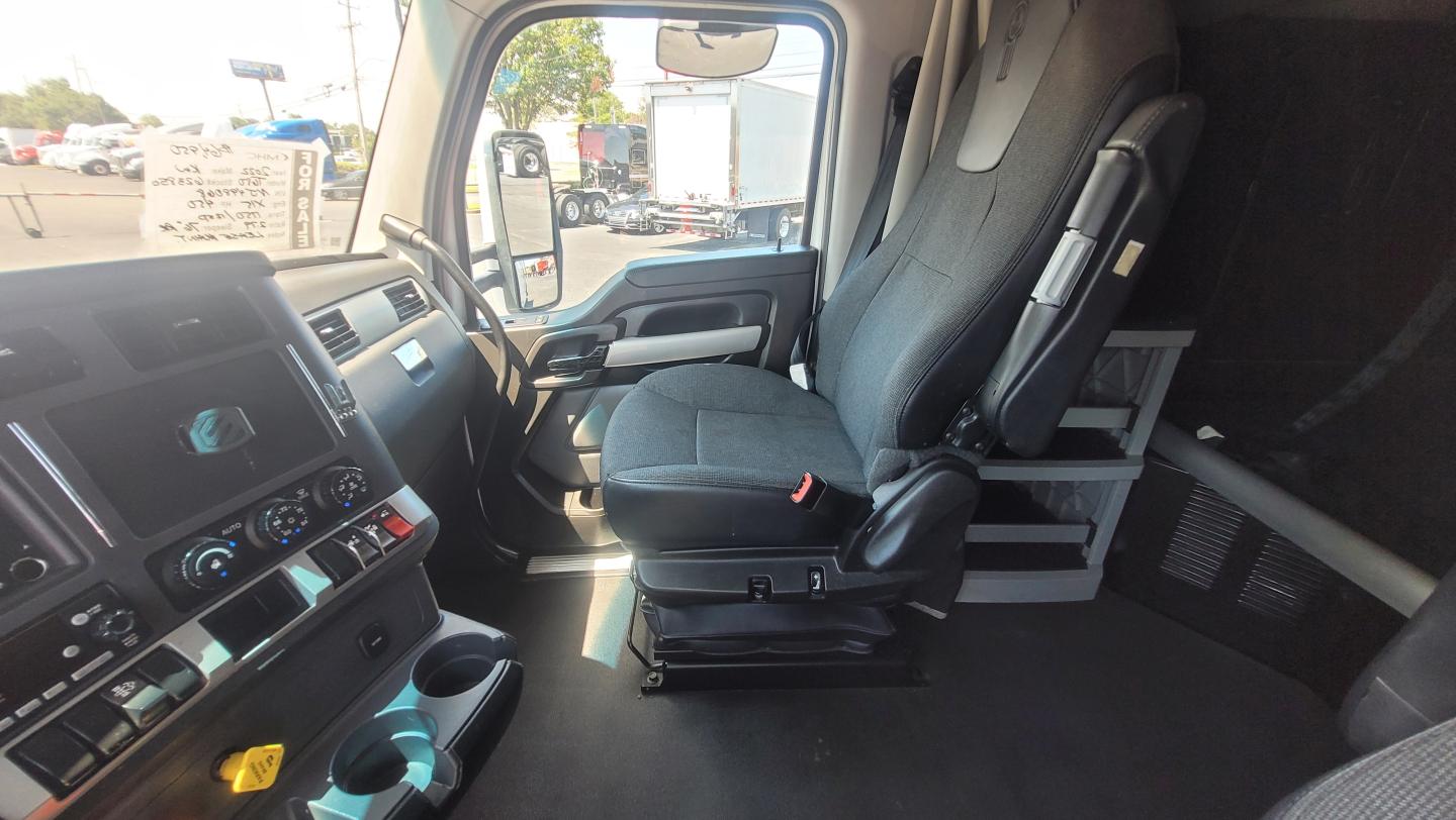 Cab interior of a 2022 Kenworth T680 truck showing front seats and dashboard. Visible text on controls and panel, but no legible model details beyond generic vehicle cabin features.