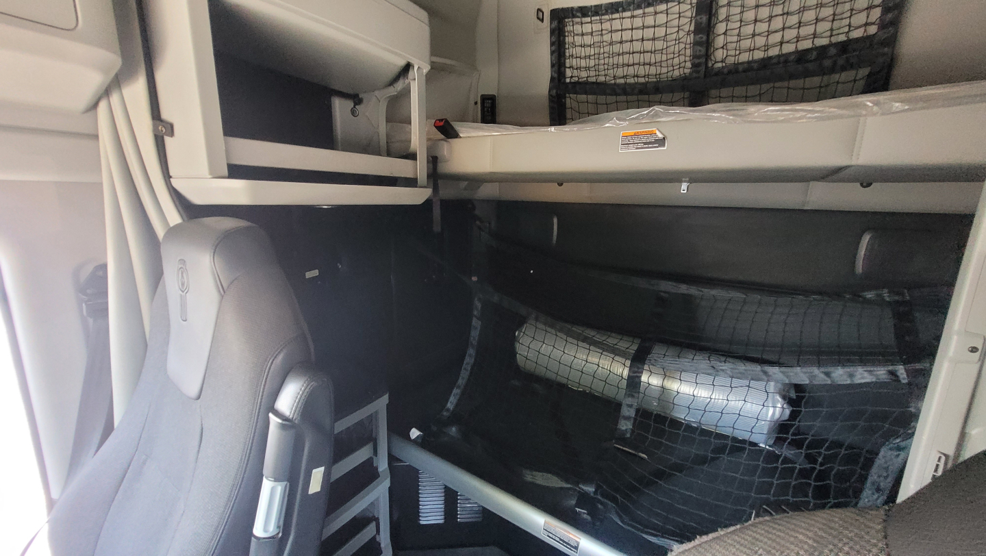 Kenworth T680 sleeper cab interior showing storage shelves and partition with netting.