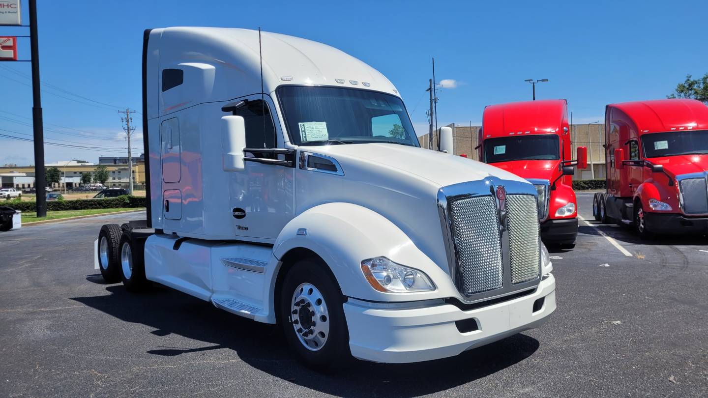 2022 Kenworth T680 semi-truck in a dealership lot, white sleeper cab, front grille, and side mirrors visible.