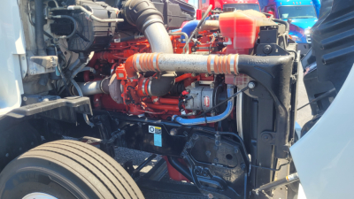 Kenworth T680 engine bay showing red engine and various hoses and components.