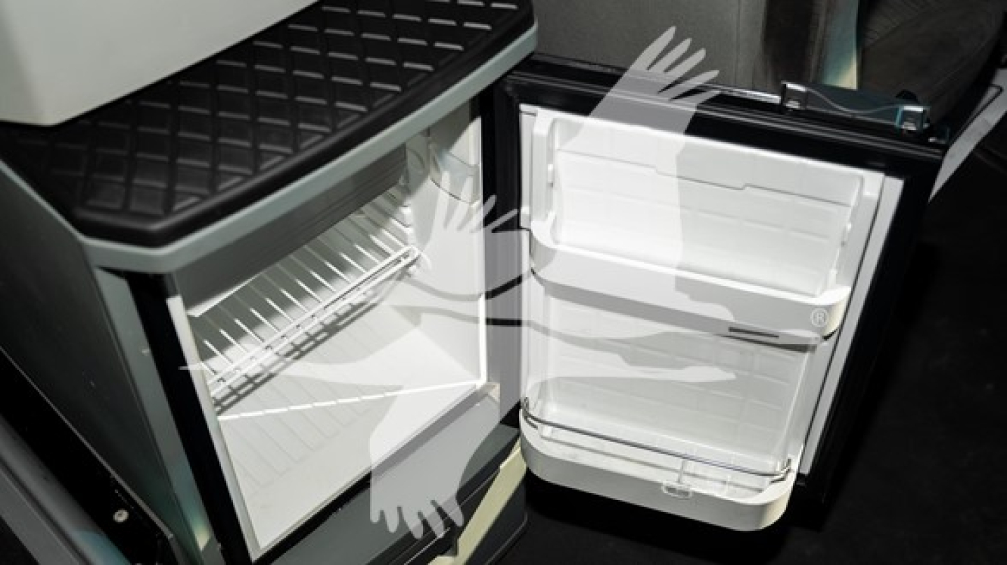 Kenworth T680 cab interior showing open under-bench refrigerator-freezer? and compact fridge with shelves and door shelves.