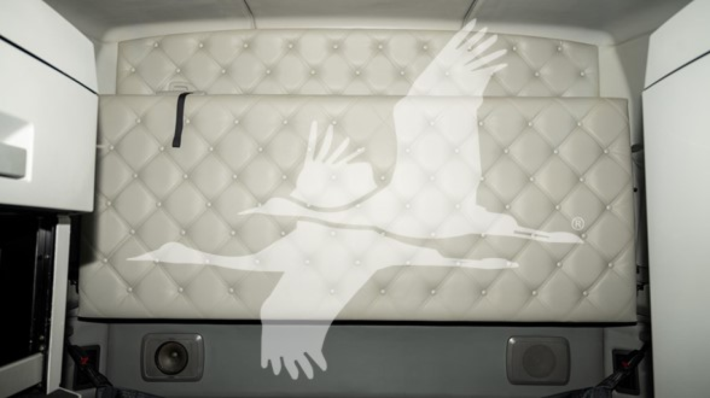 Vehicle interior wall with tufted white padding and a large stylized bird graphic; no legible text visible.