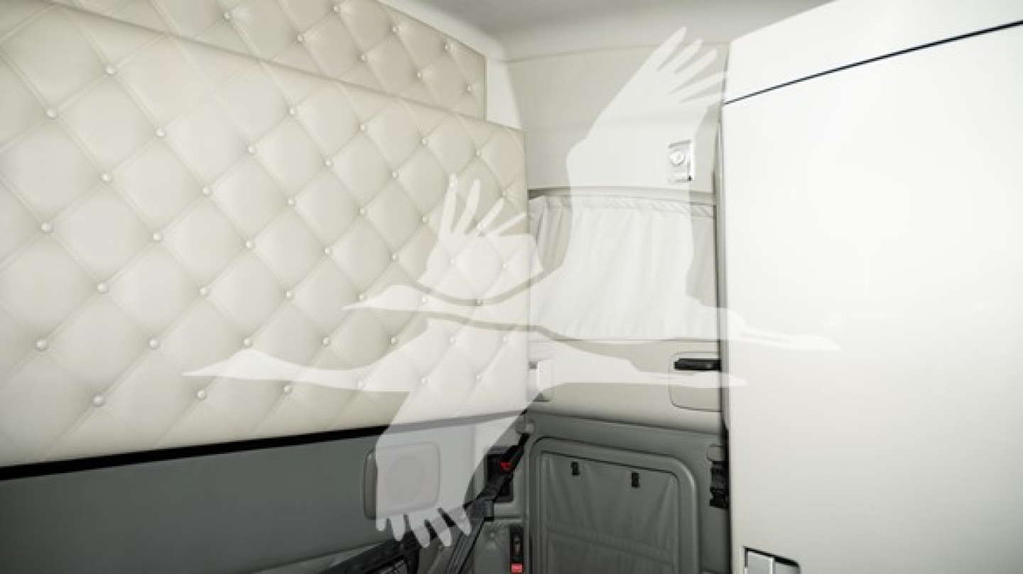 Kenworth T680 sleeper cab interior showing quilted headliner and storage panel, with light gray upholstery and panel seams.
