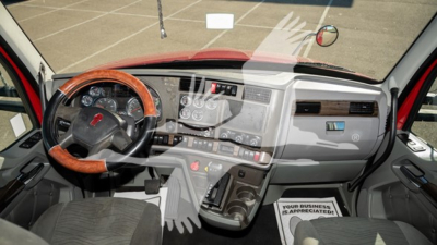 Truck cab interior: steering wheel with wood trim, instrument cluster, center console with controls, gray dashboard, gear shifter, and a passenger floor mat.