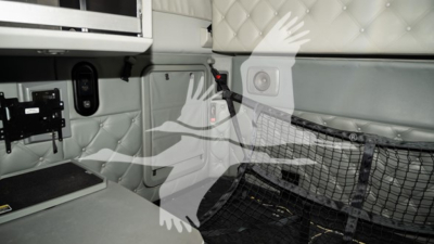 Kenworth T680 sleeper cab interior with quilted upholstery, storage area, and mesh cargo net. Visible is a small rectangular panel and a black strap.