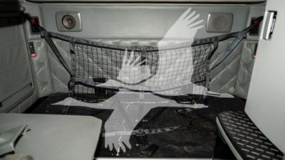 Kenworth T680 truck sleeper interior back area with cargo net and side storage; interior panels and floor visible.