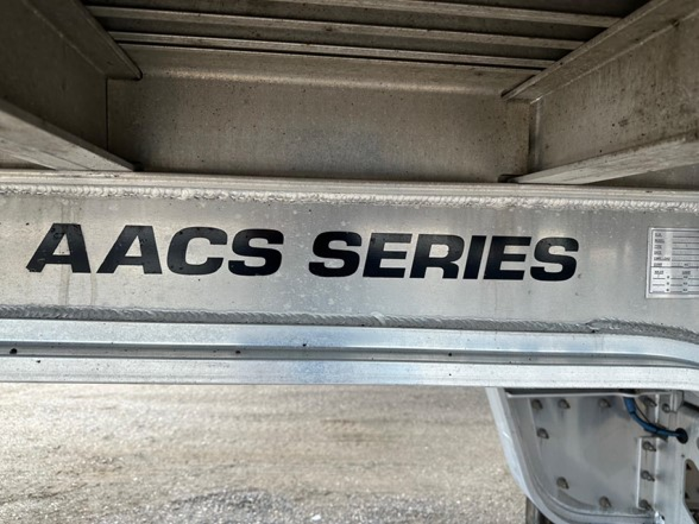 AACS SERIES label on a trailer chassis beam showing metallic finish and black lettering.