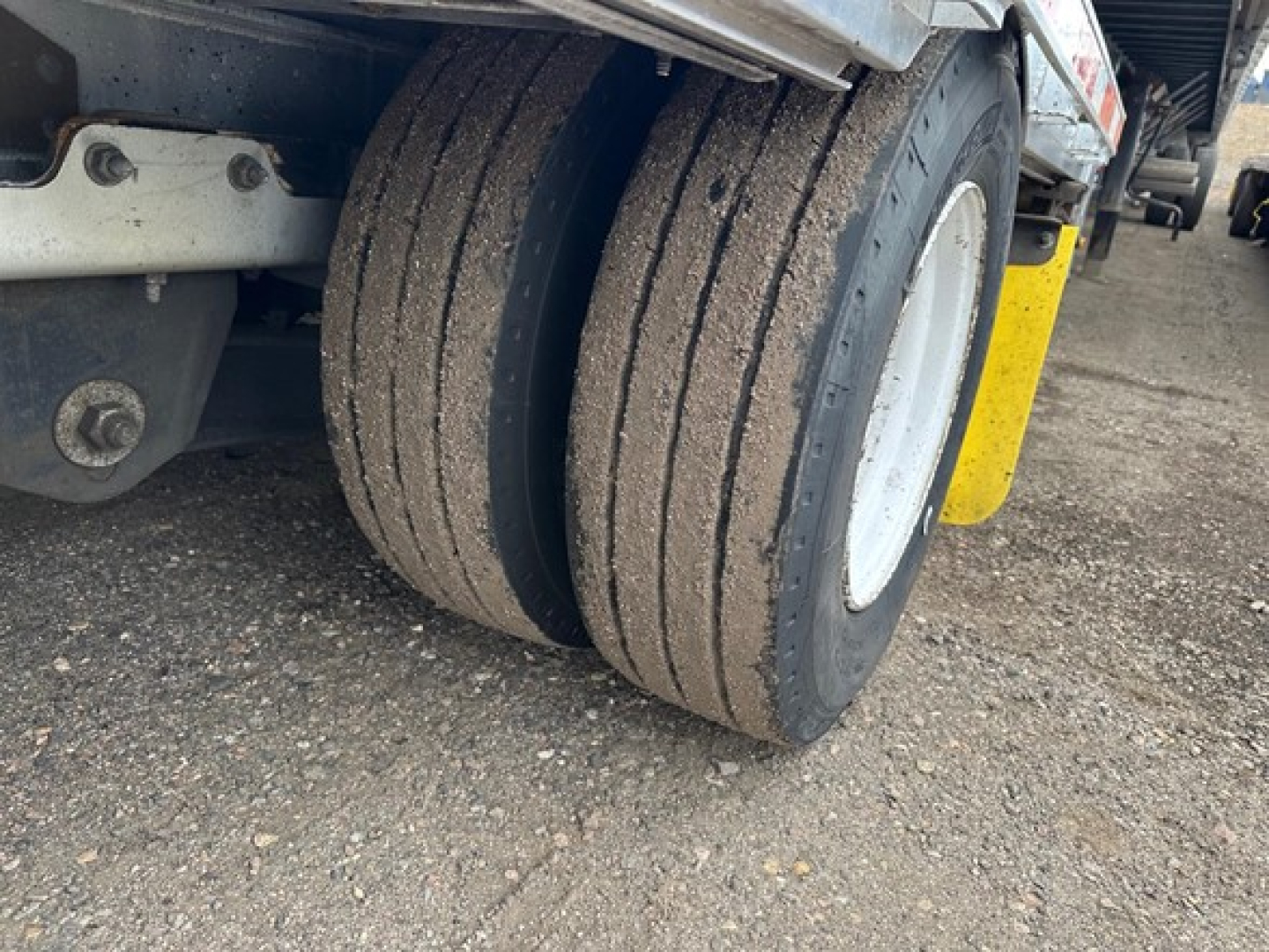 Trailer dual-tire setup with dirt on tires, rear view of 2016 Trail King all aluminum drop deck trailer showing dual wheels and mudguard.