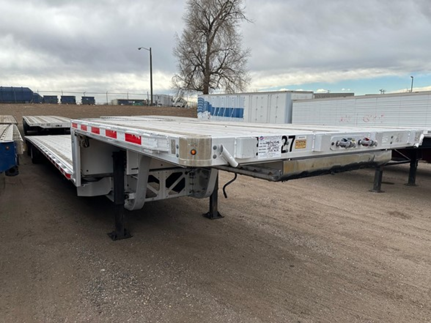 Trail King all aluminum drop deck trailer showing long flat deck and front landing gear with tag and safety decals