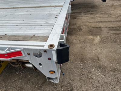 Drop deck trailer corner showing aluminum bed, rear corner with tail light and modular fitting. Visible are aluminum surface, side rail, and black bumper or bumper cover.