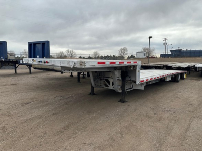All-aluminum Trail King drop deck trailer with extendable gooseneck and multiple axles, side rails, and warning lights. Flatbed surface visible with landing gear down.
