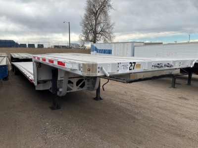 Trail King all aluminum drop deck trailer showing long flat deck and front landing gear with tag and safety decals