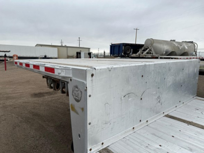All-aluminum Trail King drop deck trailer side view showing aluminum flatbed with riveted panels and rear wheel wells, weathered surface.