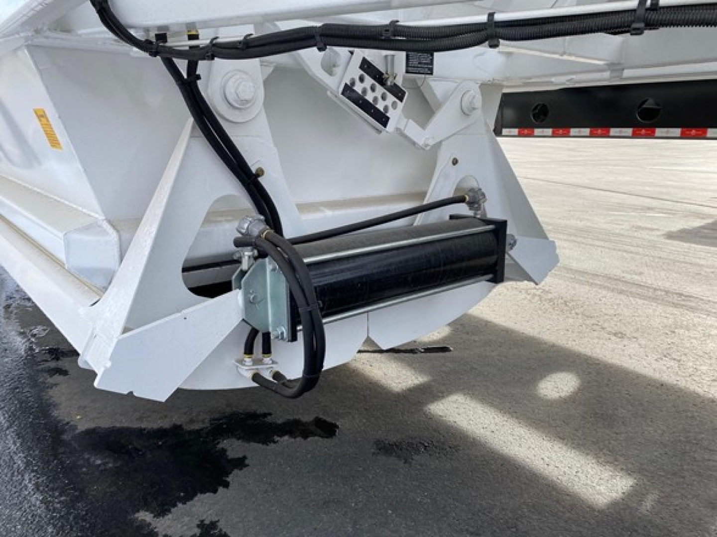 Ranco LW21-40 dump trailer component showing hydraulic cylinder and mounting hardware with black roller and white painted frame.