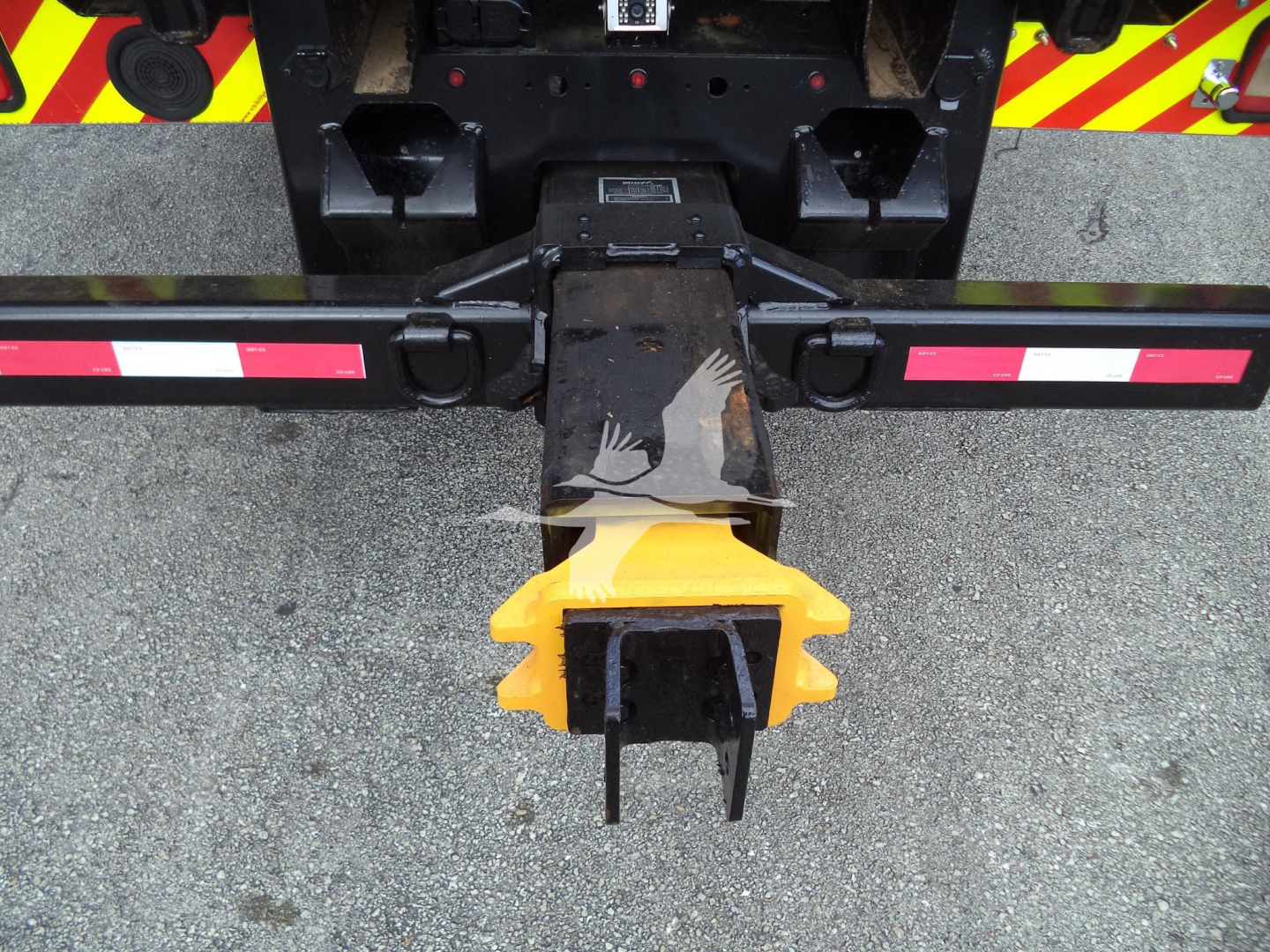 Truck rear hitch with yellow protective pin and black hitch assembly on rollback truck.