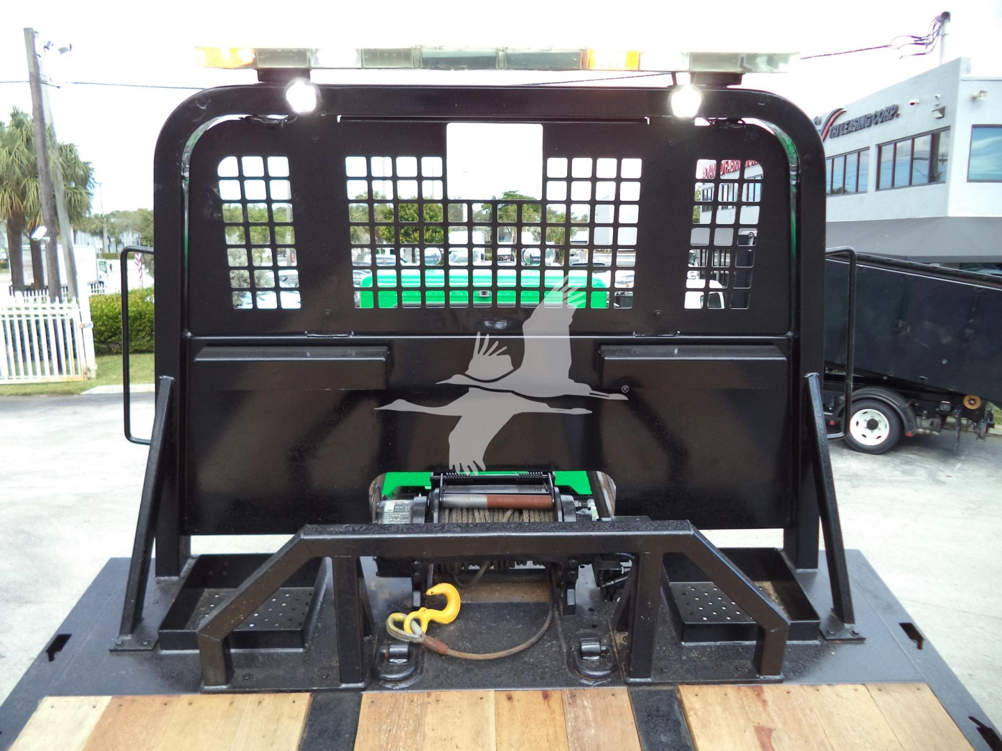 Peterbilt 348 rollback bed with cage and hydraulic hookup visible, light bumper and metal grid behind cab portion.