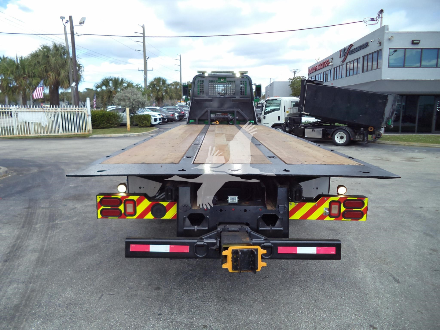 Peterbilt 348 rollback truck rear view showing flatbed and hitch with yellow safety beacon; license plate area and red/white reflective stripes visible.
