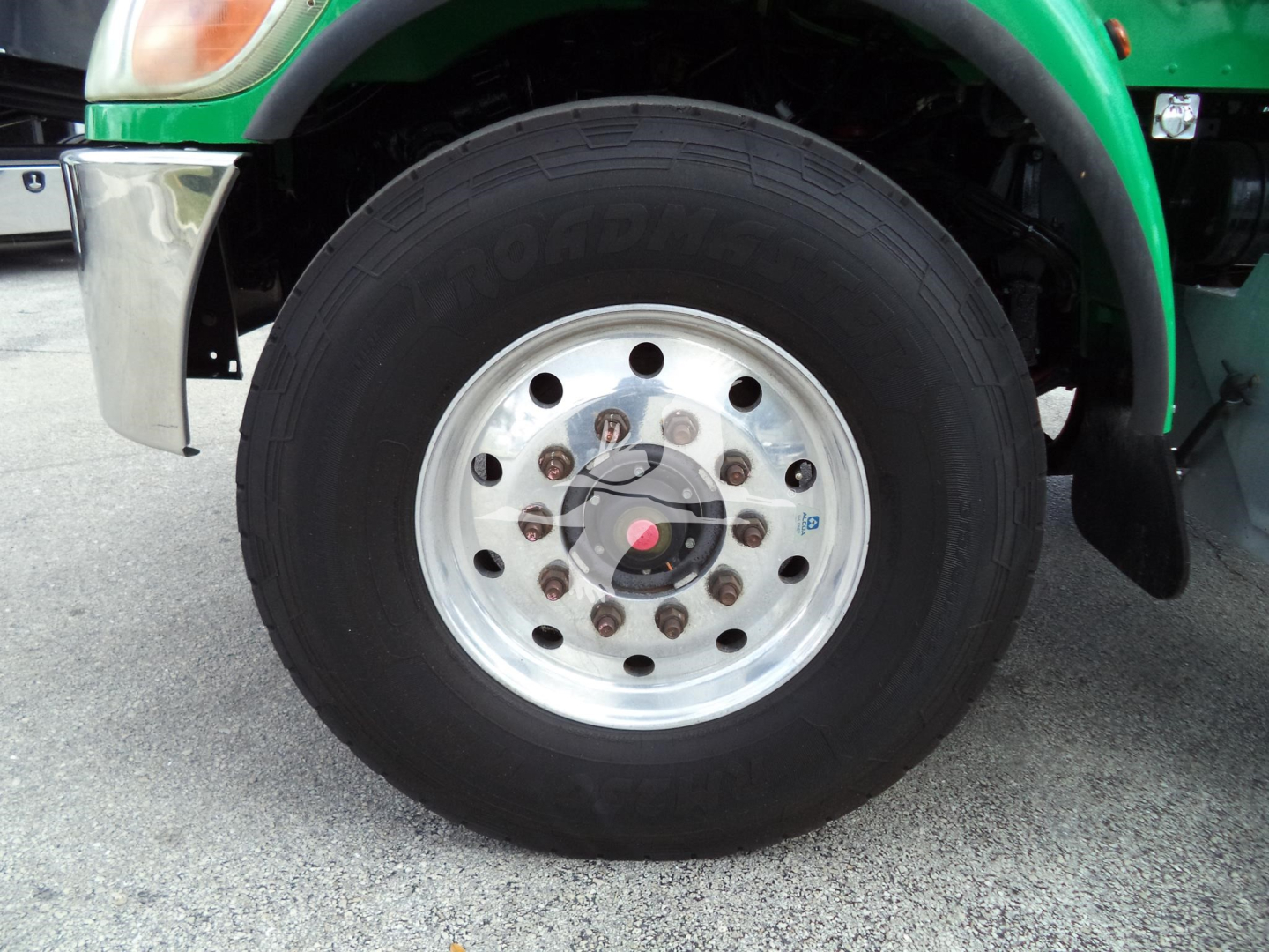 Peterbilt 348 wheel and front fender showing polished steel wheel with multiple lug nuts and green body panel.